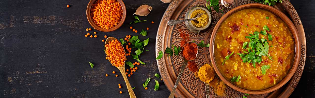 Indian dal. Food. Traditional Indian soup lentils. Indian Dhal spicy curry in bowl, spices, herbs, rustic black wooden background. Top view. Authentic Indian dish. Banner. Flat lay