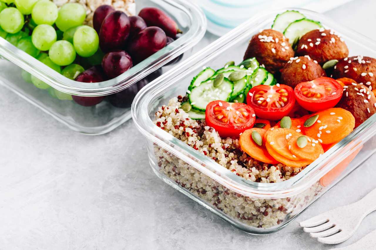 Meal prep lunch box containers with quinoa, meatballs cucumbers, carrots and pumpkin seeds
