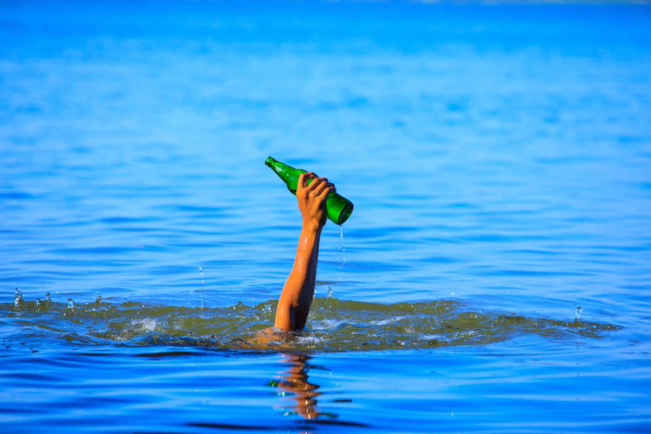 male hand holding bottle picking up from the water, hands picking up garbage from the water,man collects trash,Garbage collection with rivers,seas,Environment